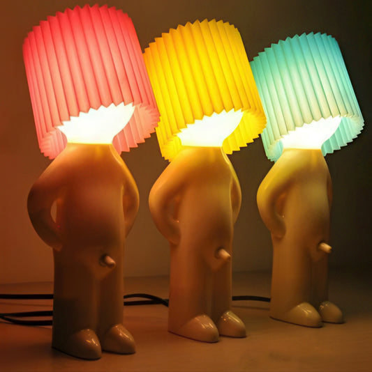 Three cute little shy boy table lamps with colorful diffusers on a neutral background