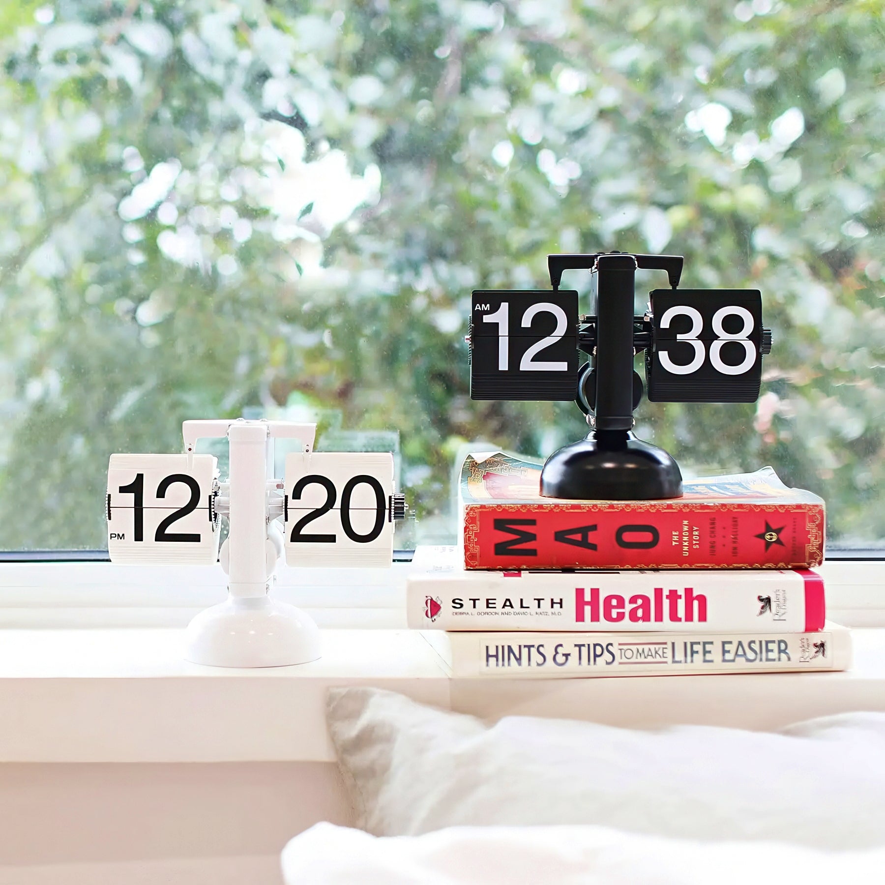 Flip clock on books with a blurred green outdoor background