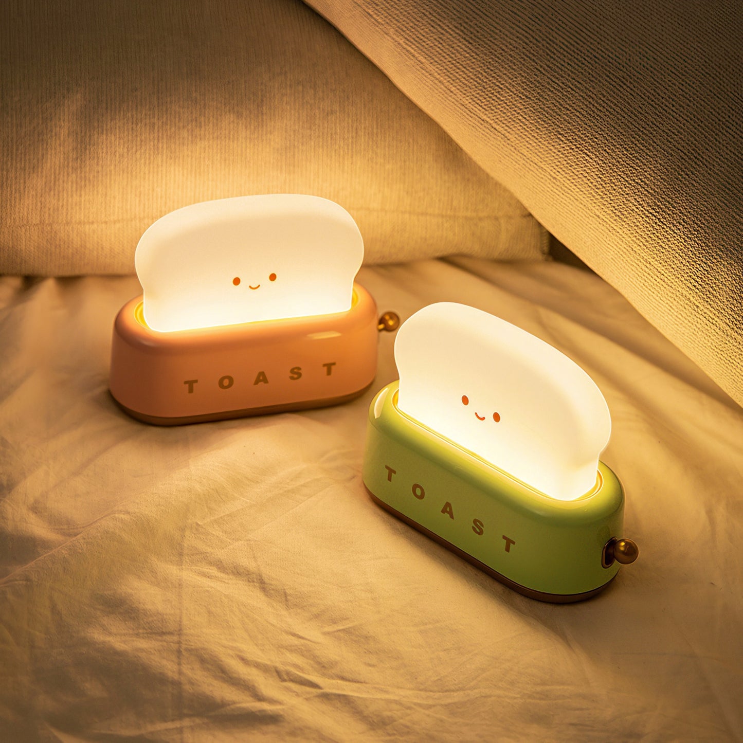 Two cute night lights shaped like slices of toast on a bed.
