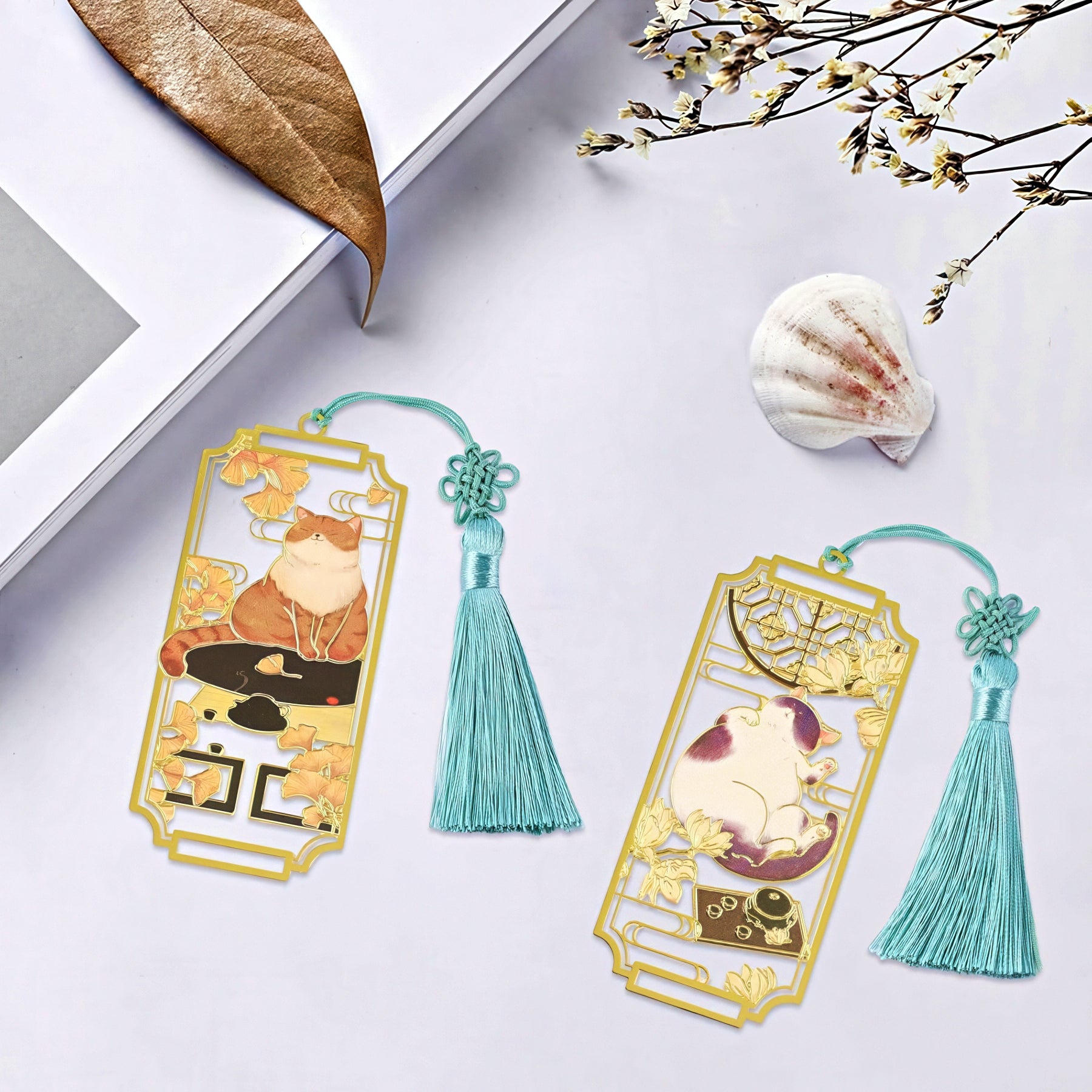 Two decorative bookmarks with tassels and cat designs on a white surface.