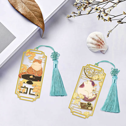 Two decorative bookmarks with tassels and cat designs on a white surface.