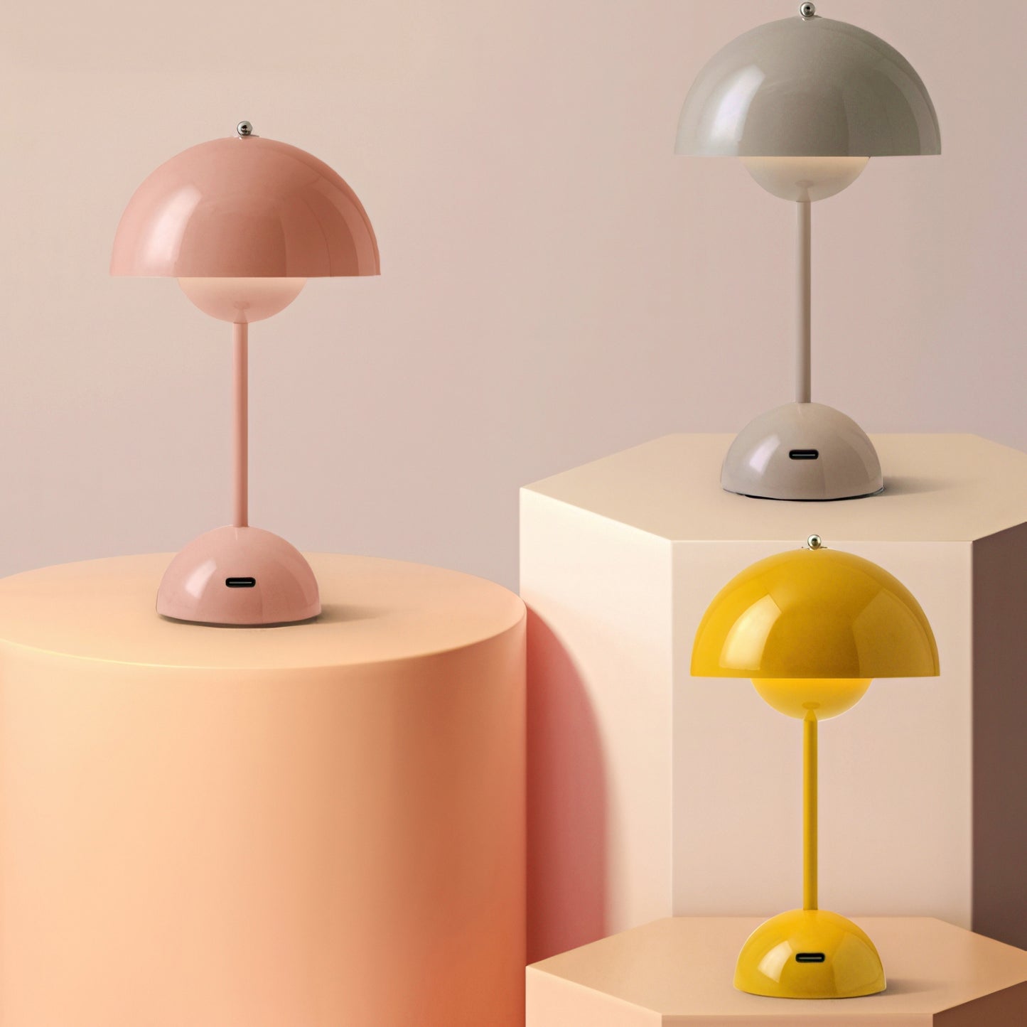 Three table lamps on geometric podiums against a beige background
