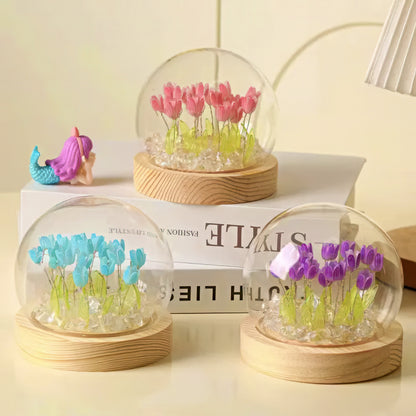 Three transparent glass spheres with colorful tulip decorations on a wooden base.
