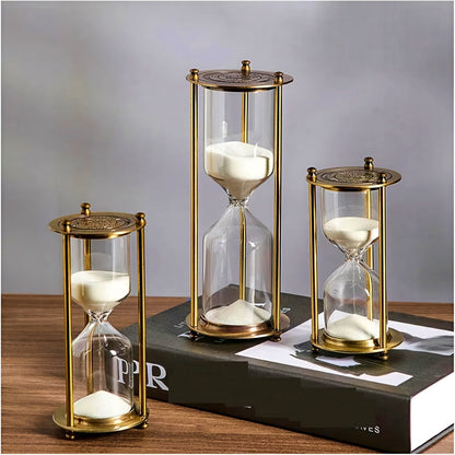 Three gold hourglasses on a wooden surface with a gray background