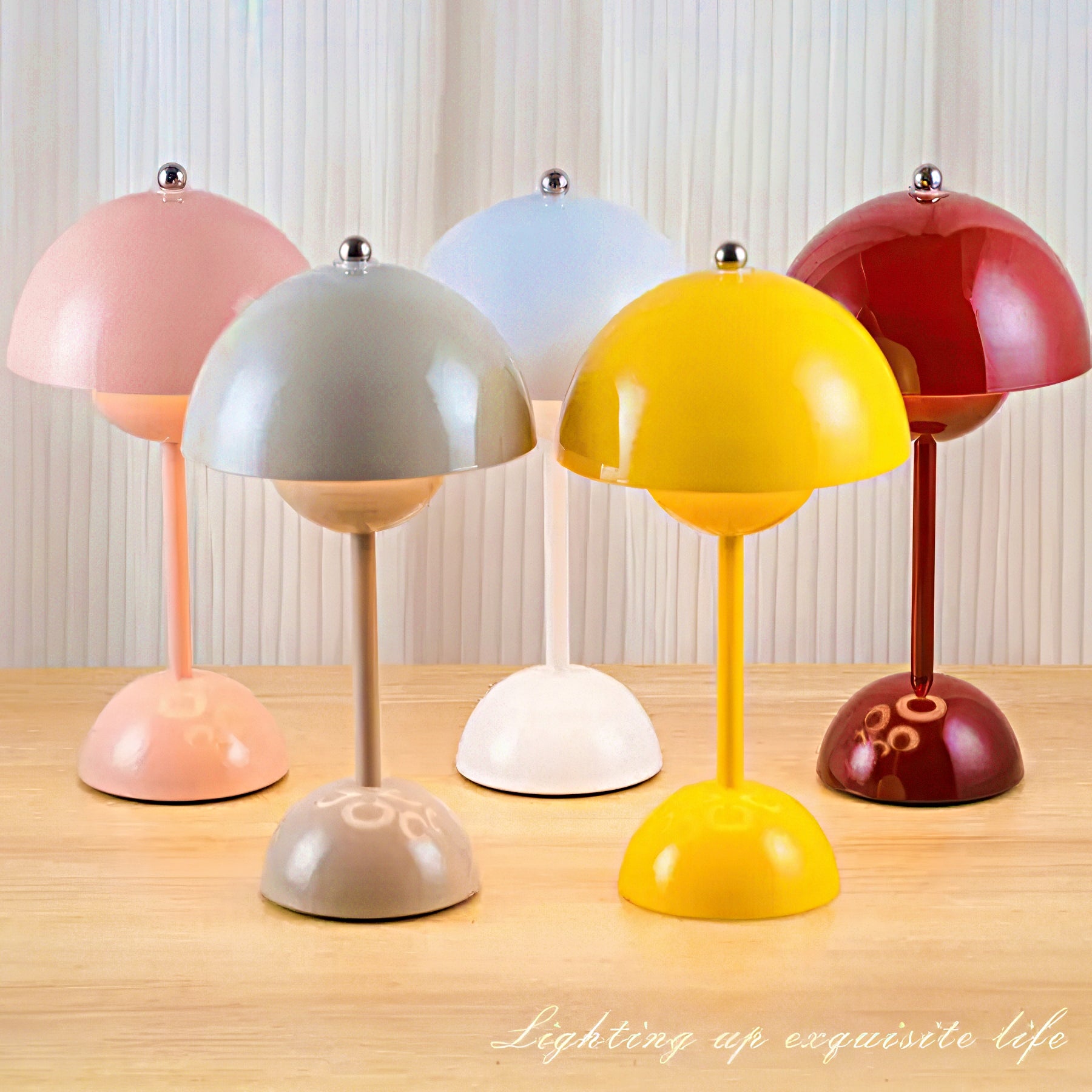 Five colorful table lamps on a wooden surface with a neutral background.