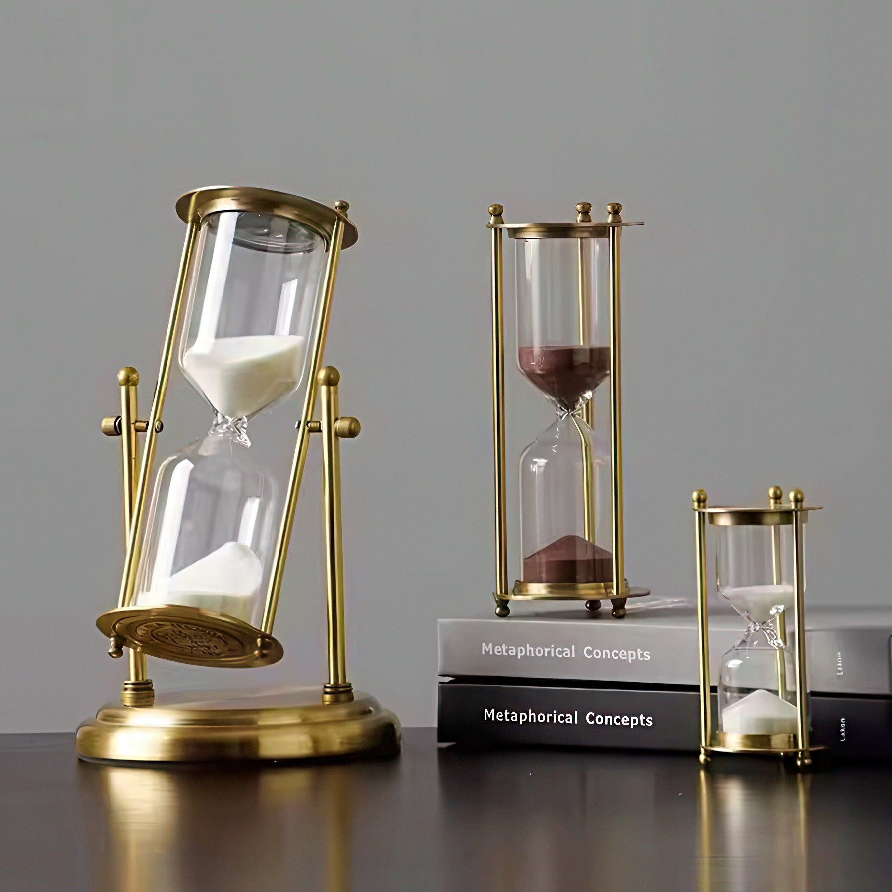 Three gold hourglass models on a gray background