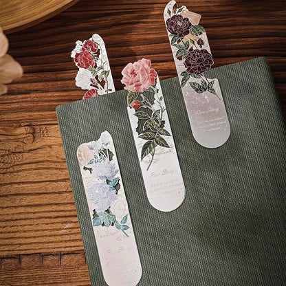 Floral bookmarks on a green book with a wooden surface background