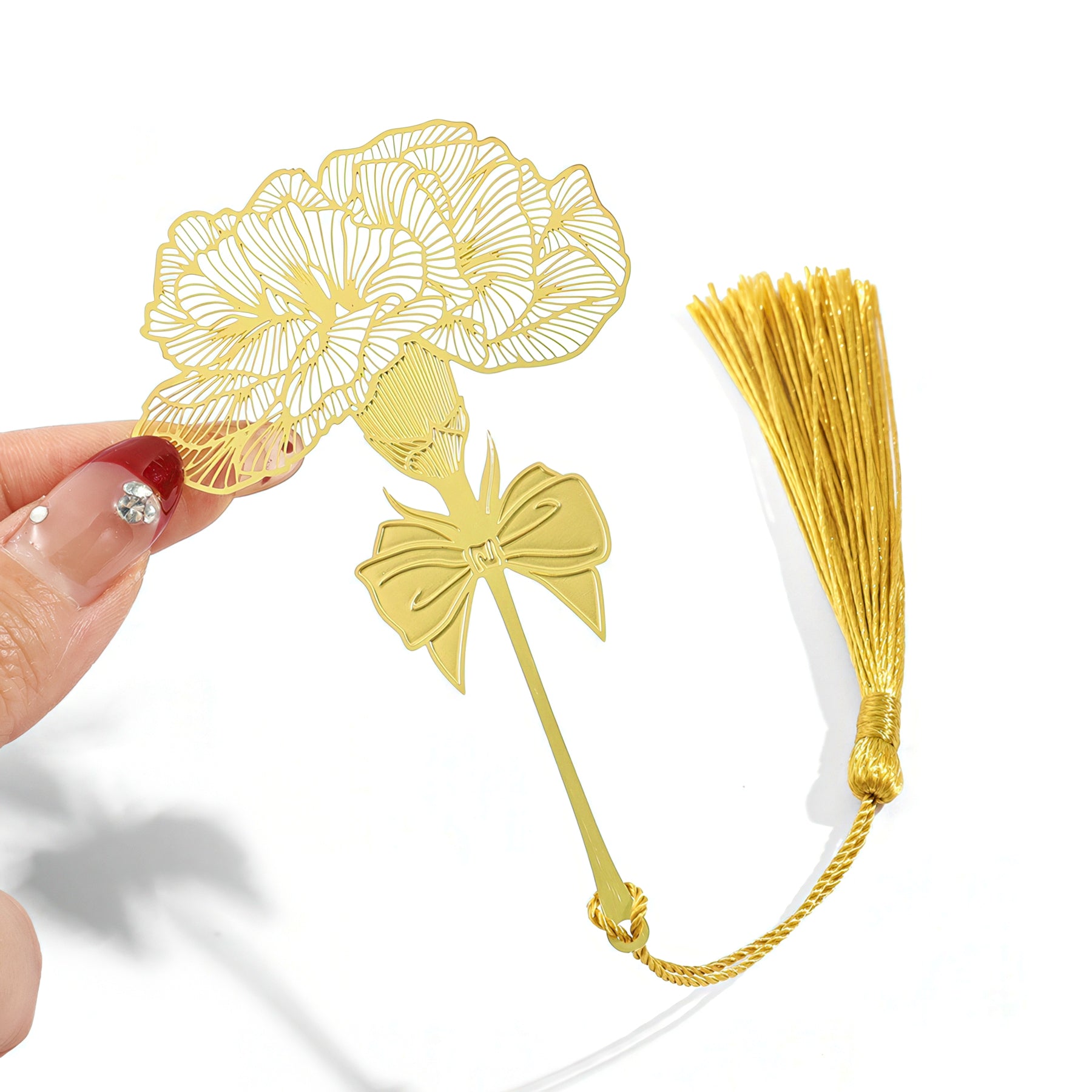 Gold floral metal bookmark with tassel held by a hand