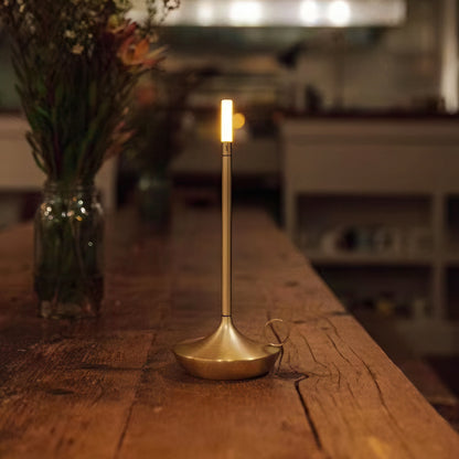 Brass candle holder shaped table lamp on a wooden table, blurred background