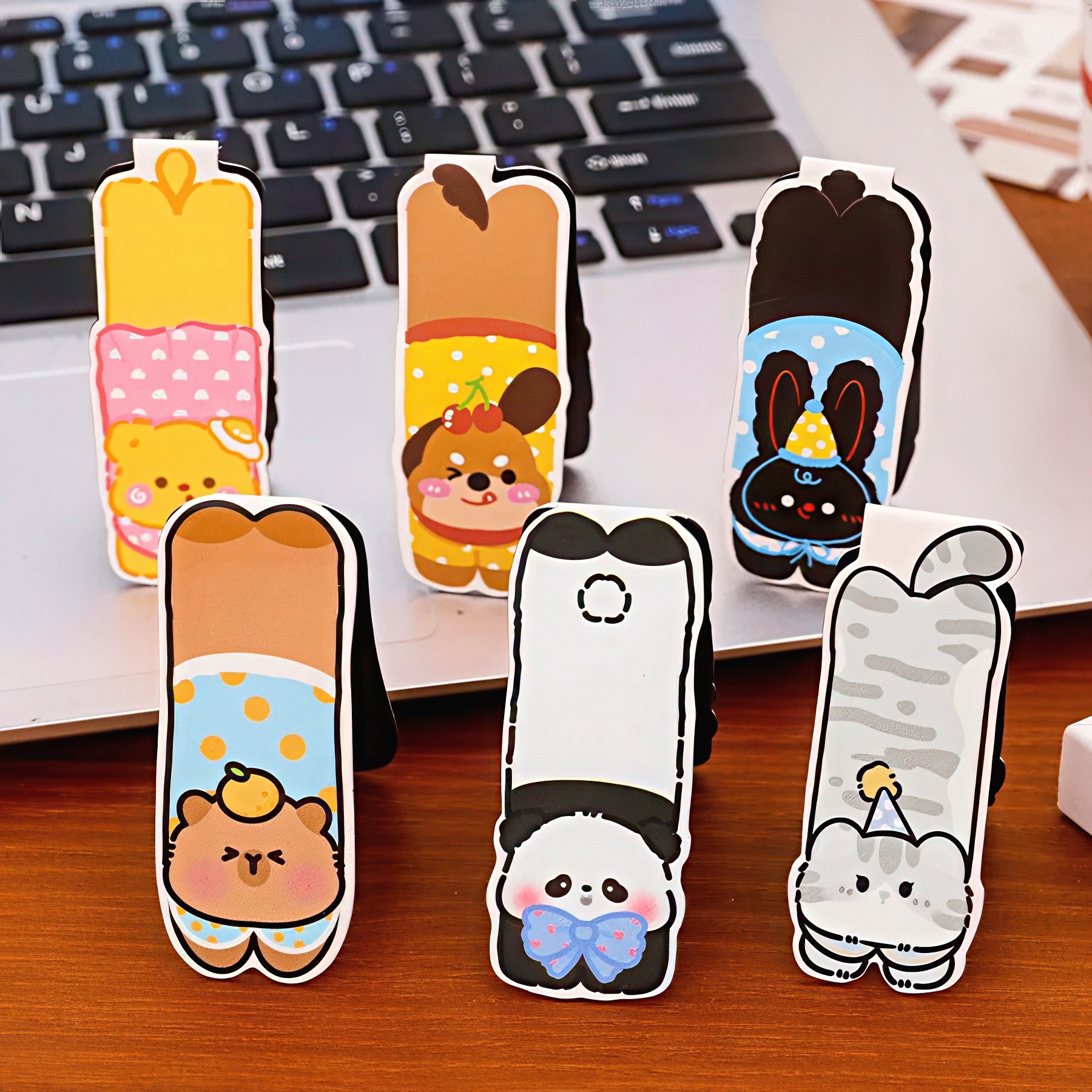 Set of pet-themed magnetic bookmarks on a desk with a laptop in the background