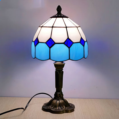 Tiffany-style table lamp with blue and white stained glass shade on a wooden surface.