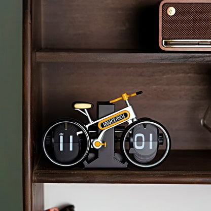 Bicycle-shaped clock on a shelf with a brown box above it