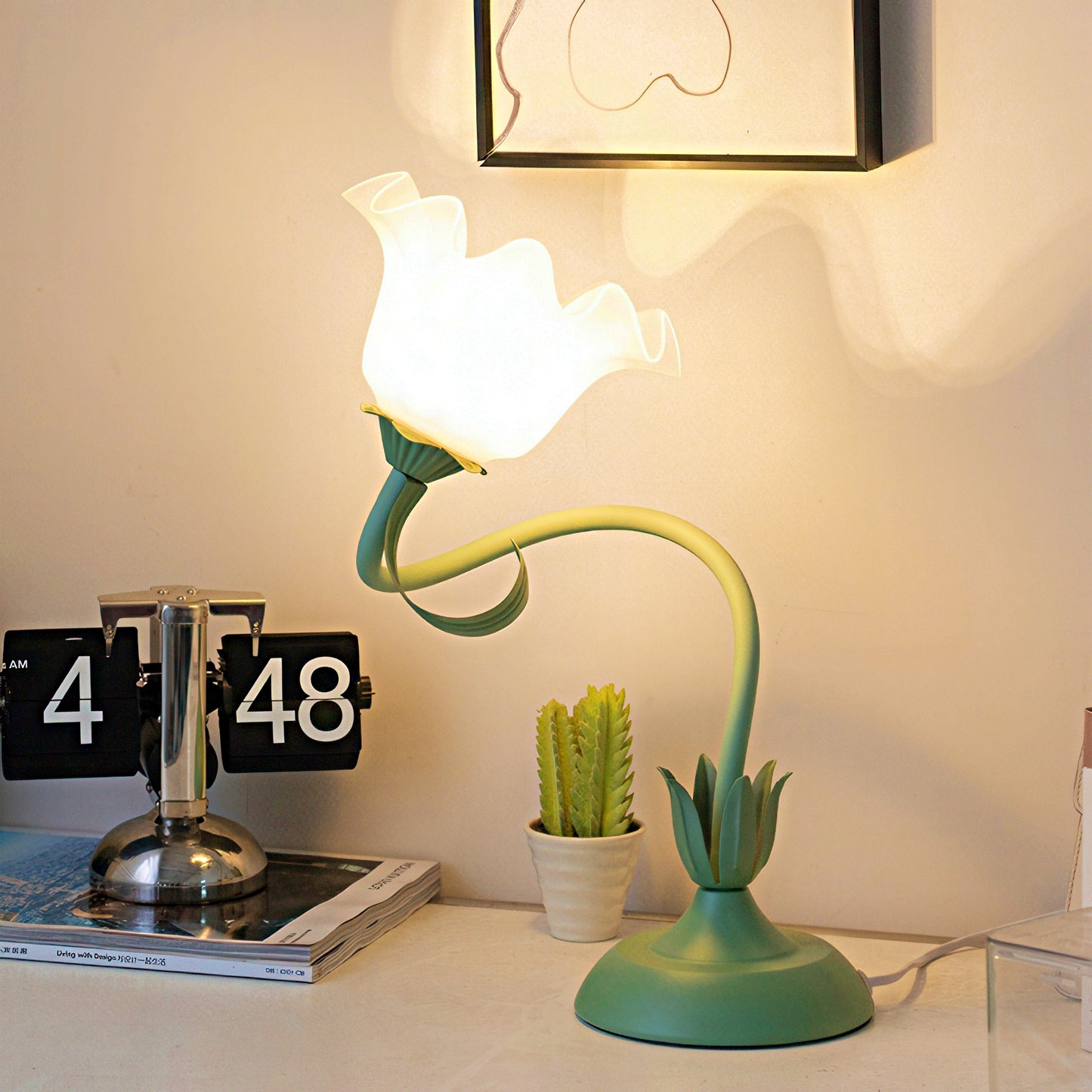 Green floral table lamp on a desk with a flip clock.