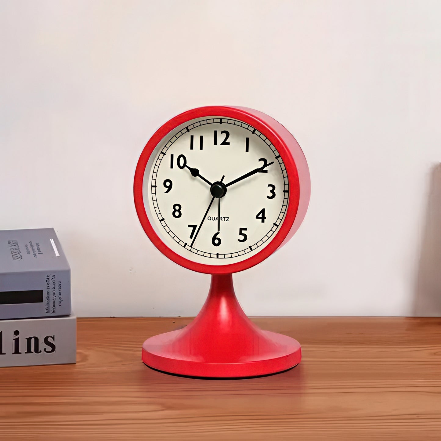 Red table clock on a wooden surface with a white wall background
