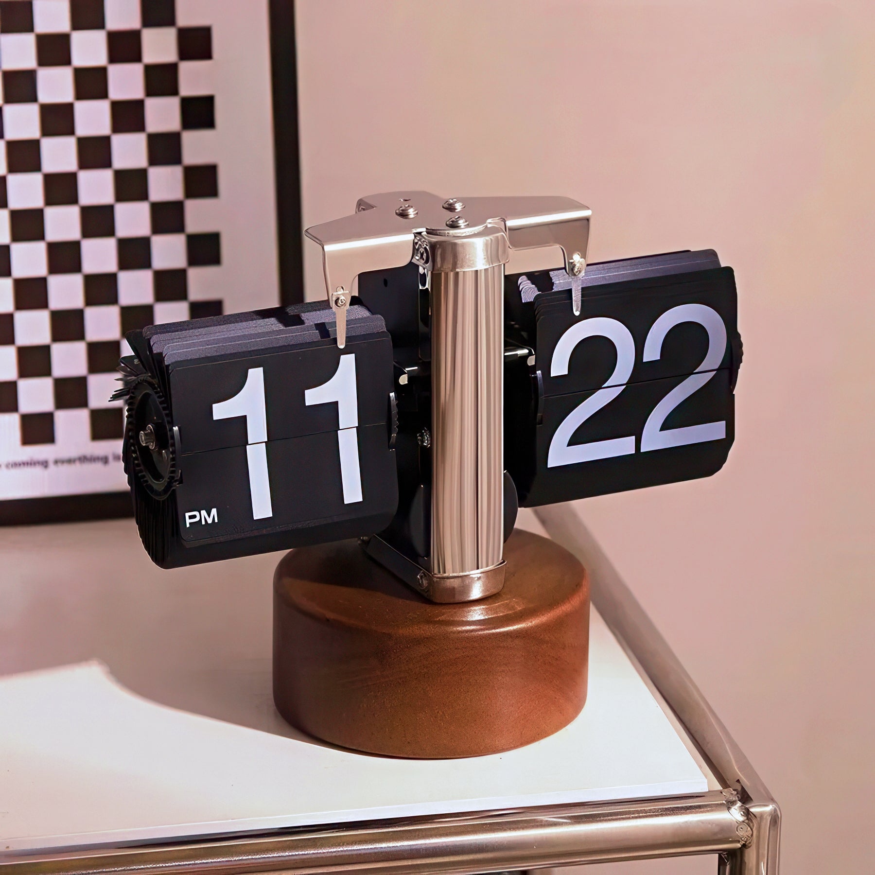 Flip clock with wooden base on a surface with a checkered wall in the background
