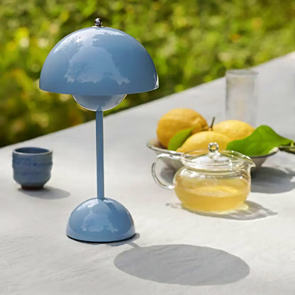 Blue table lamp on a surface with a teapot and lemons in the background