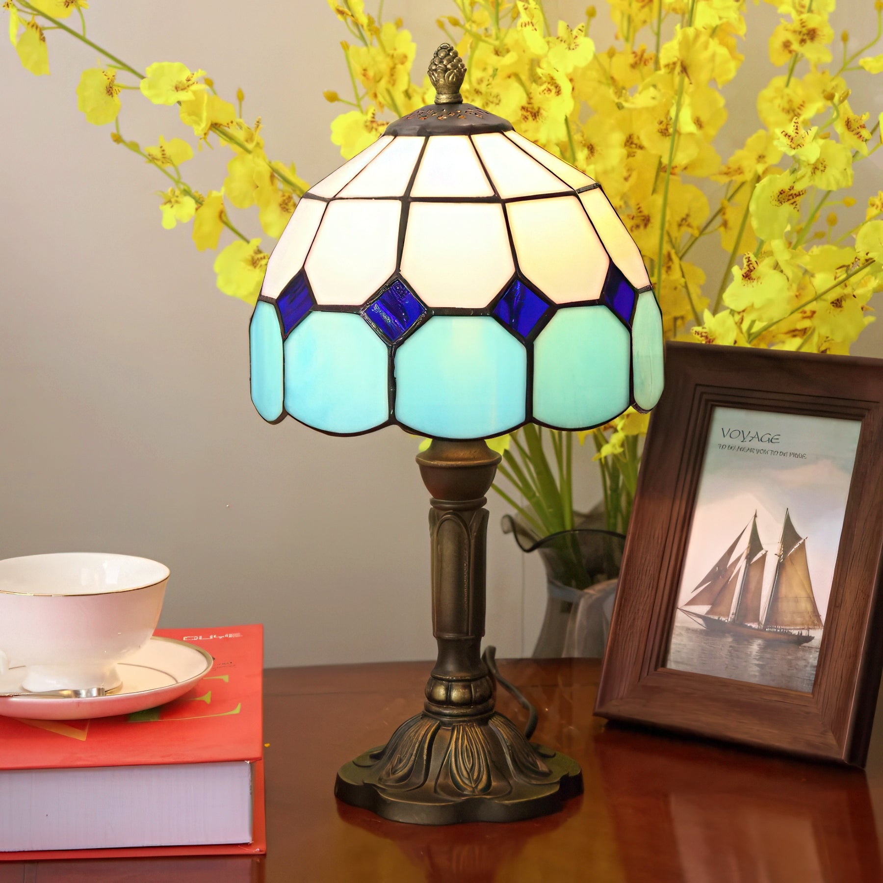 Tiffany-style lamp with stained glass shade on a table with books.