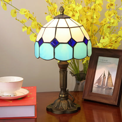 Tiffany-style lamp with stained glass shade on a table with books.