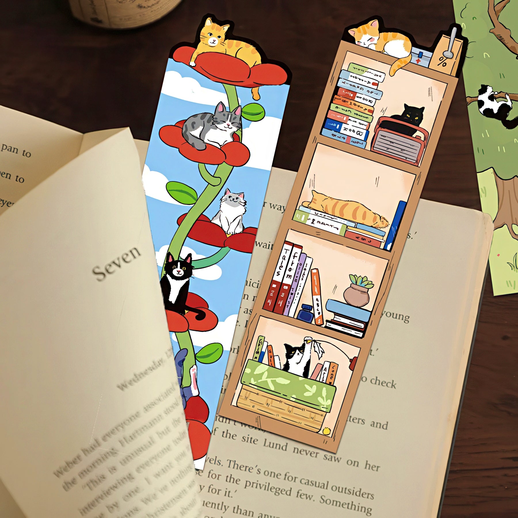 Two cat-themed bookmarks on an open book with a wooden shelf design.