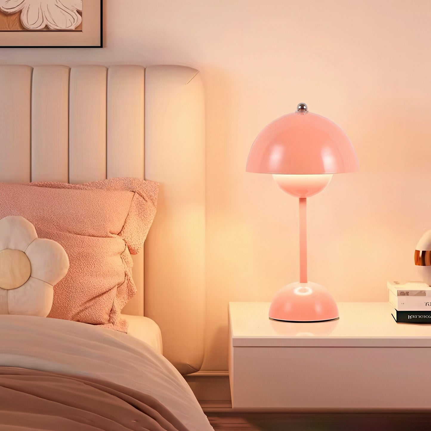Pink table lamp on a nightstand next to a bed with floral pillows