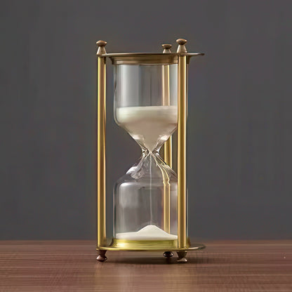 Gold-framed hourglass with sand on a wooden surface and dark background