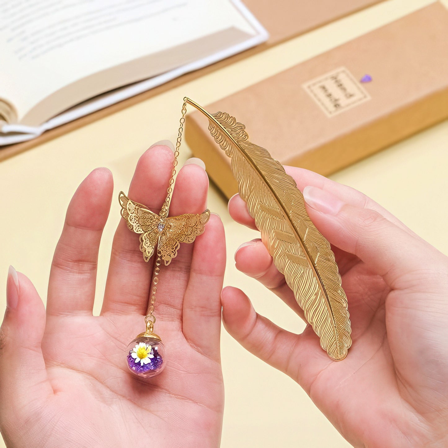 Gold butterfly and feather bookmarks held in hands with a book in the background