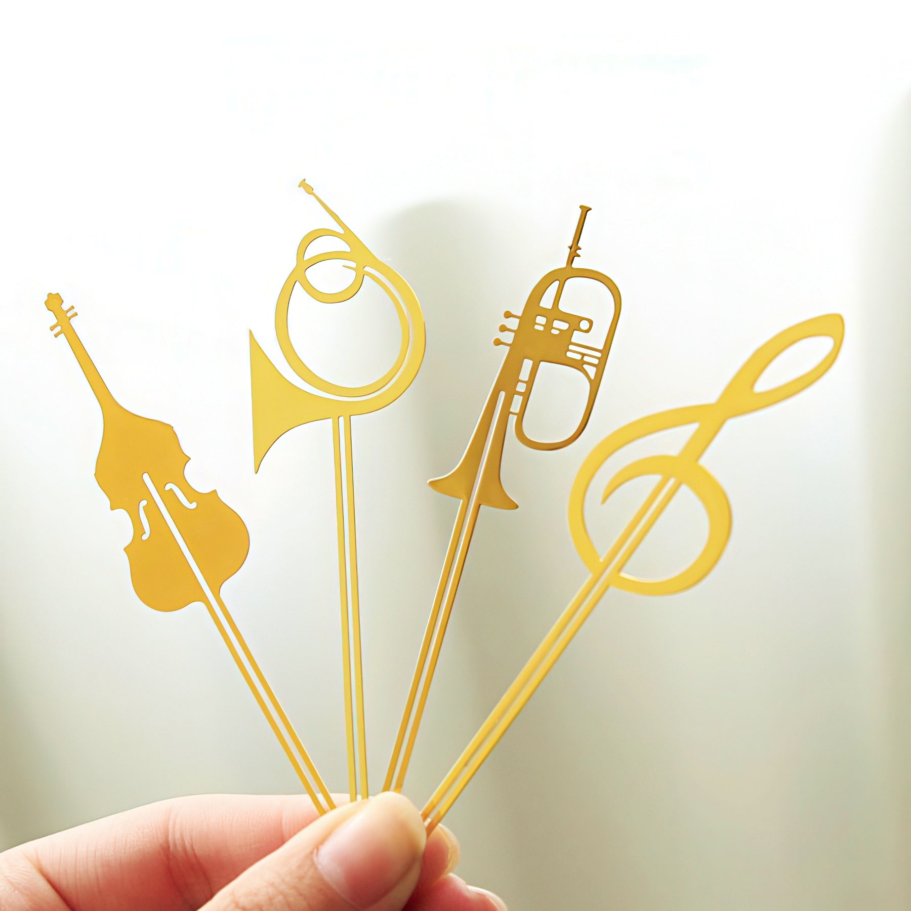 Gold musical-themed metal bookmarks held by a hand.