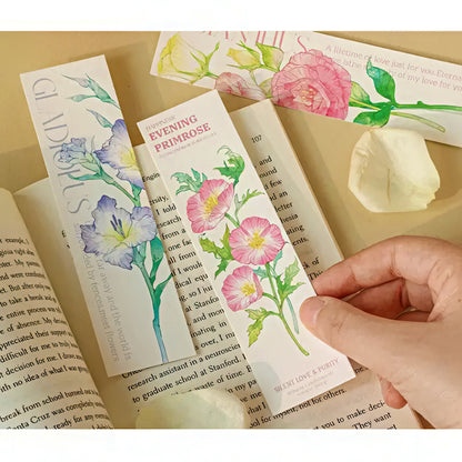 Floral paper bookmarks on an open book with a hand holding one.
