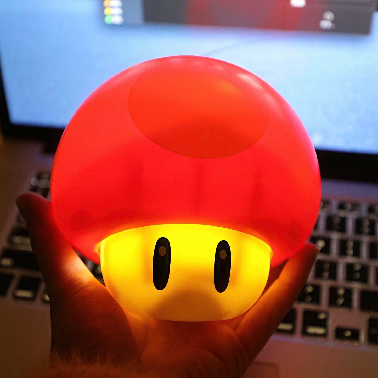 Red mushroom-shaped light held in front of a computer screen