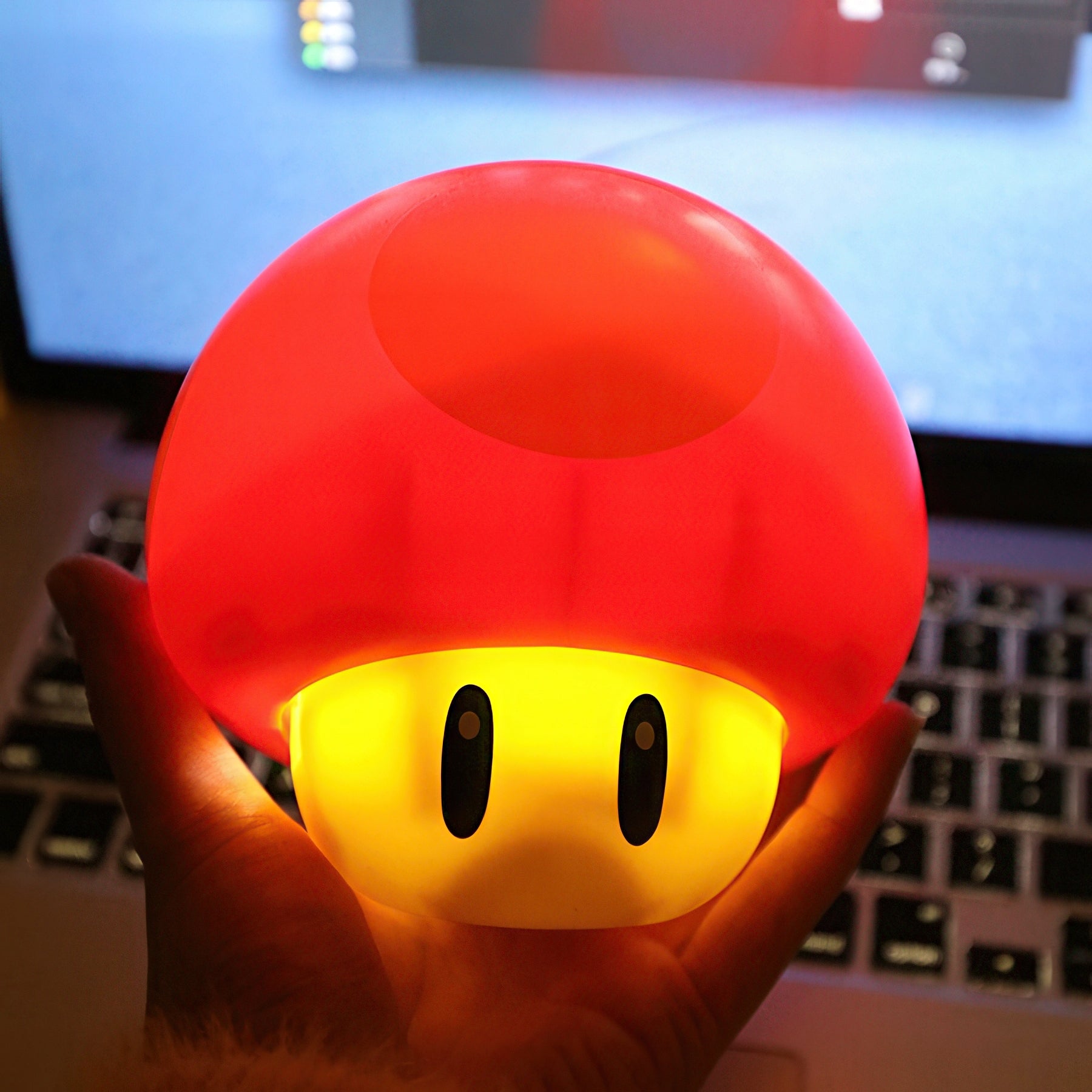 Red mushroom-shaped light held in front of a computer screen