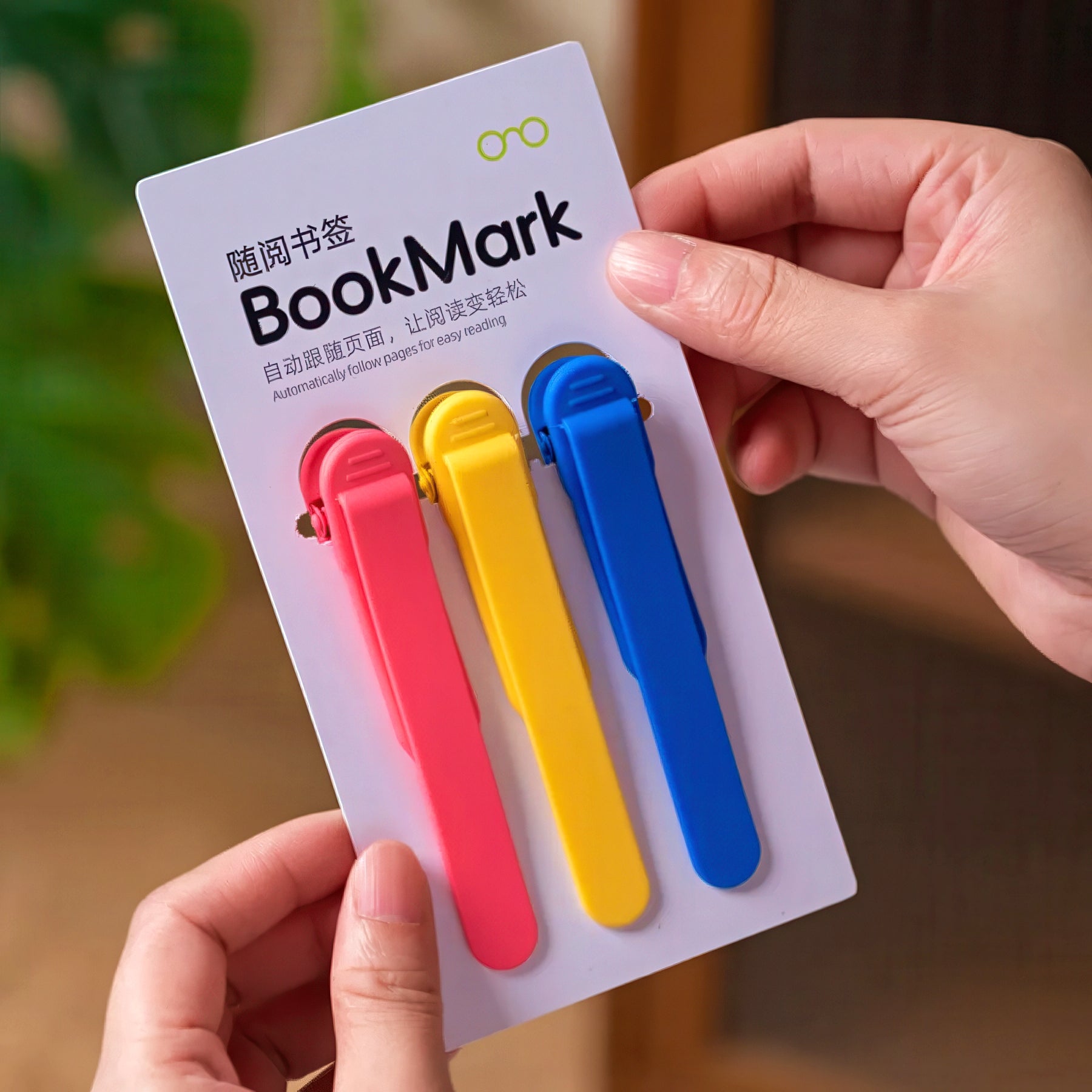 Three colorful bookmarks in a package held by a hand with a blurred background
