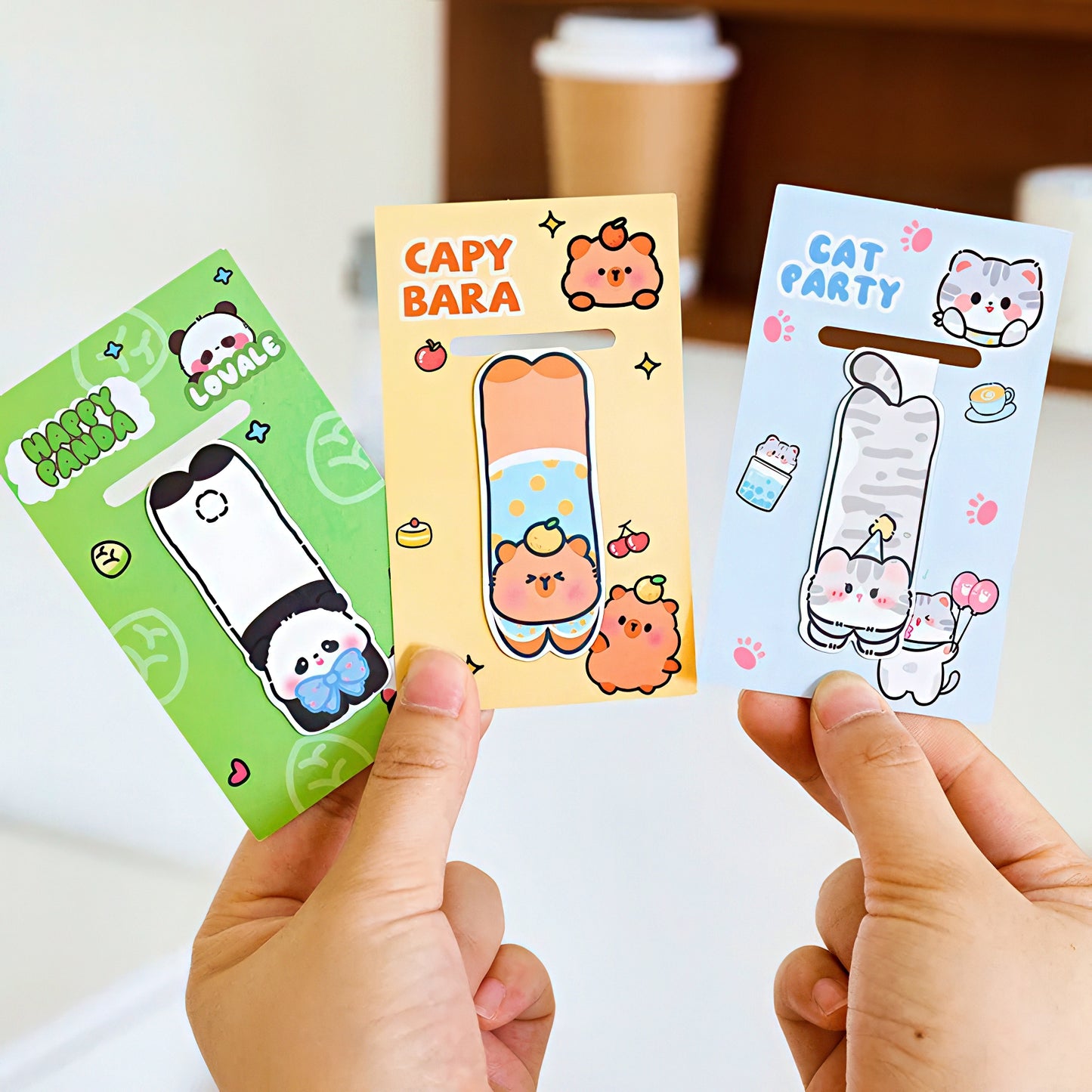 Three magnetic bookmarks with animal designs held by hands