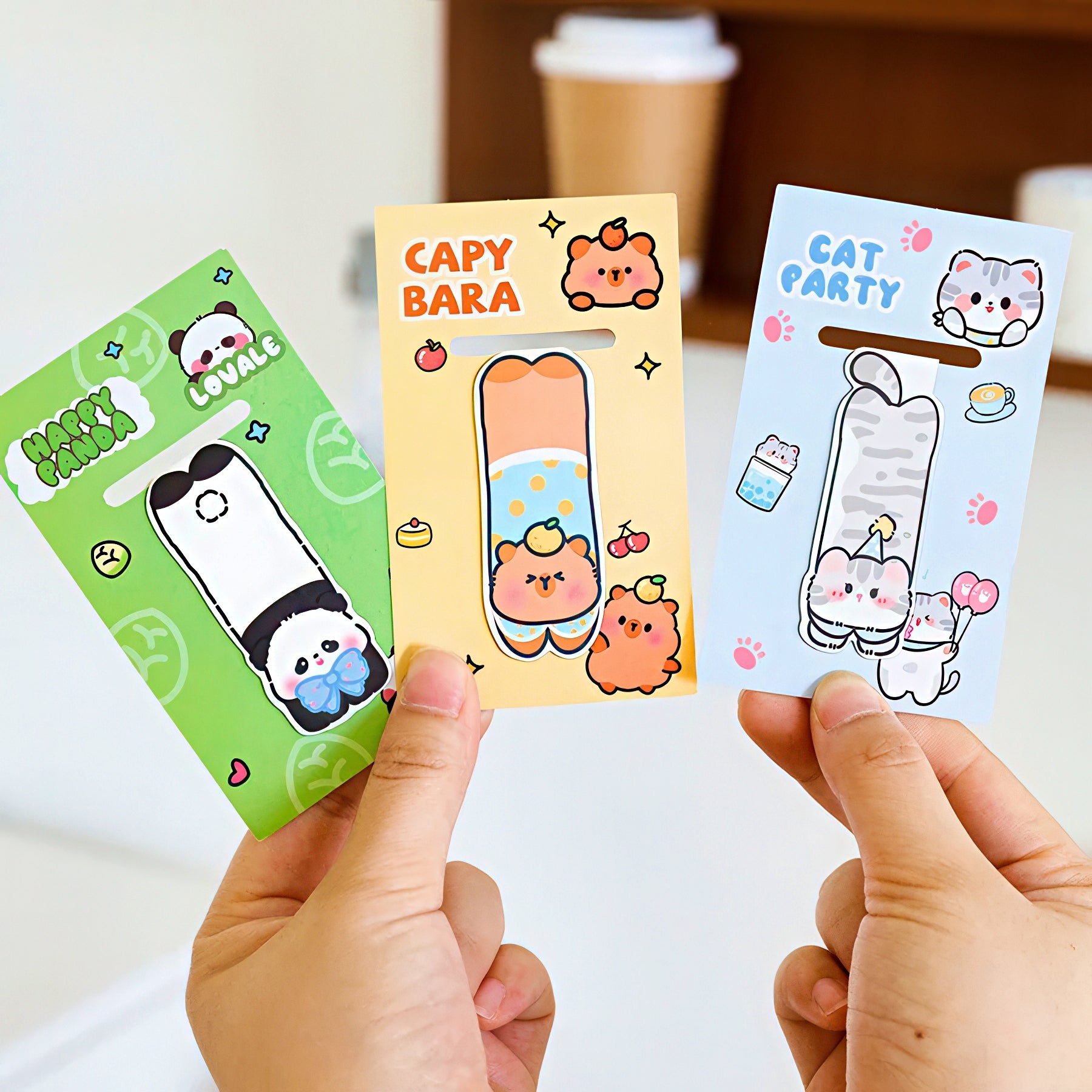 Three magnetic bookmarks with animal designs held by hands